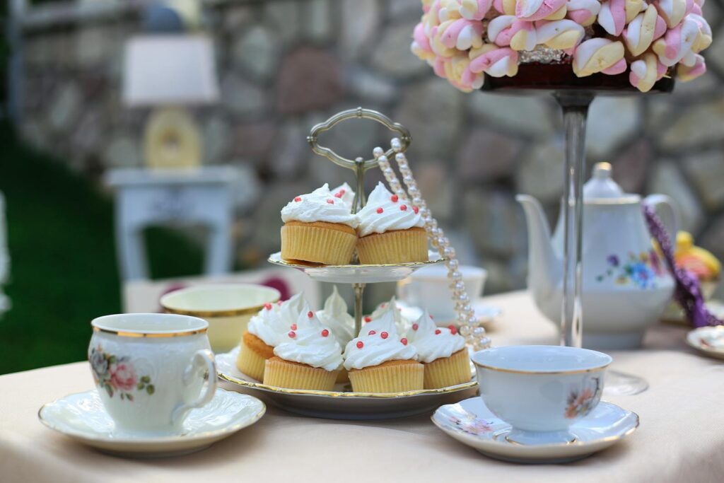 Charming tea party setup with cupcakes and porcelain tea set outdoors.