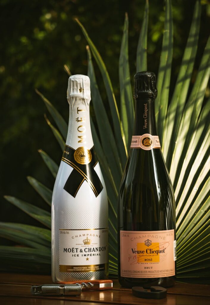 Two champagne bottles displayed against a lush, tropical backdrop with palm leaves.